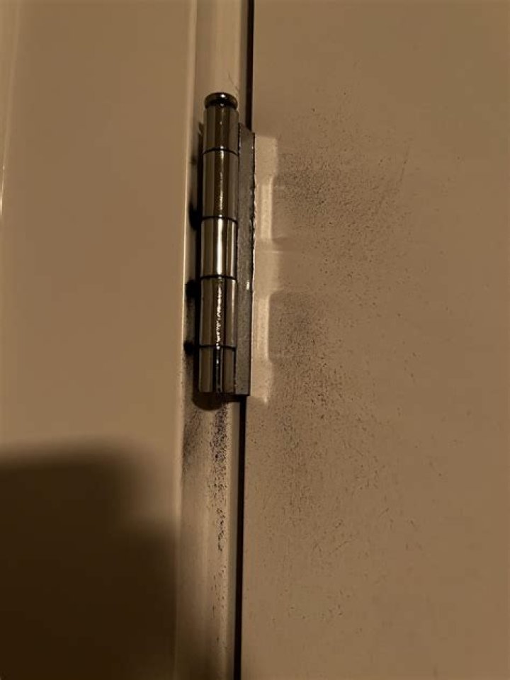 What causes black dust from door hinges?